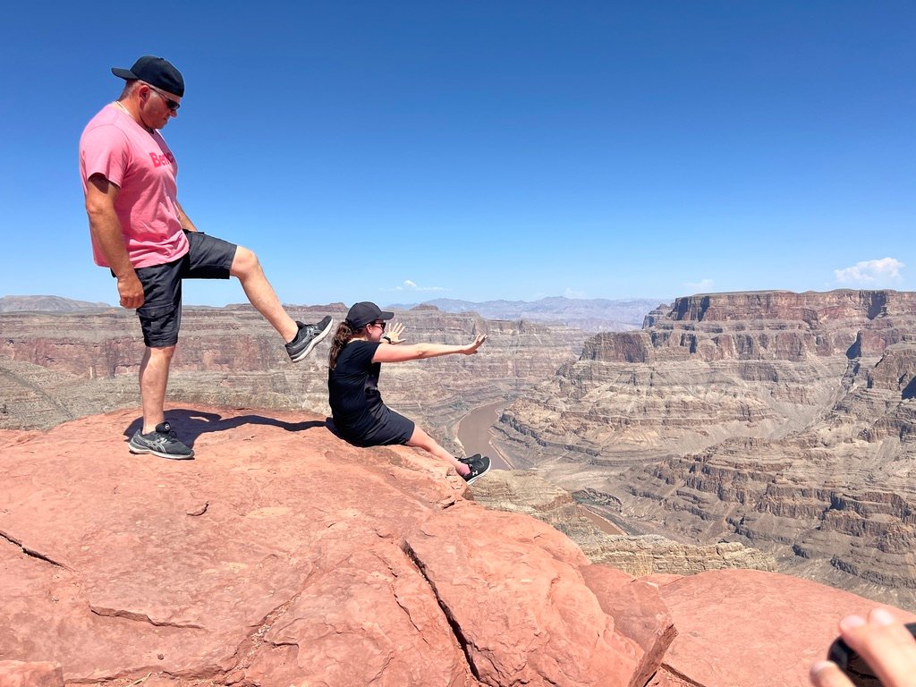 Client qui fait mine de pousser sa femme au bord du canyon à Guano Point, Grand Canyon West